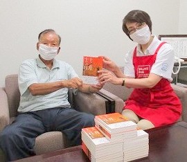 足立勝之さんから図書の寄贈をいただく様子